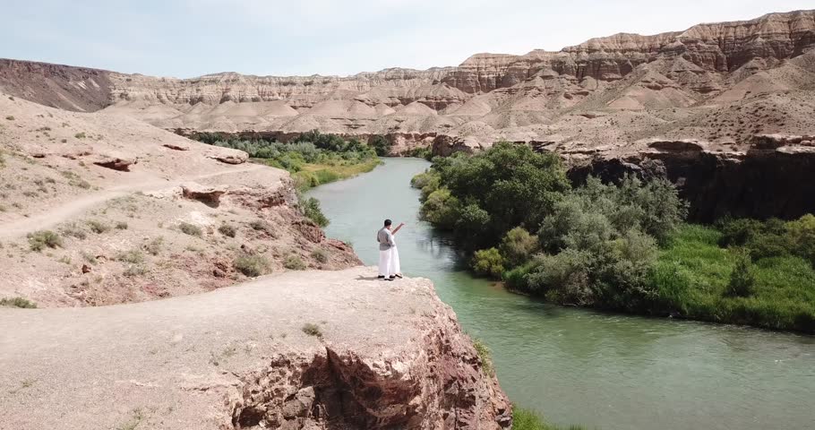 Young couple in white embracing and looking at the landscape of the river. The view starts from the cliff and moves smoothly for a couple, the river, the trees, the grass. Romantic moment of lovers.