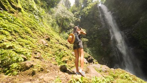 Young Traveler Woman Making Photos of Amazing Rainforest Jungle Waterfall Using Smartphone. Bali, Indonesia. 4K, Slowmotion Cinematic Steadycam Lifestyle Travel Footage.