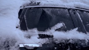 Person cleaning the side of black car of snow after storm with green soft snow brush tool before going