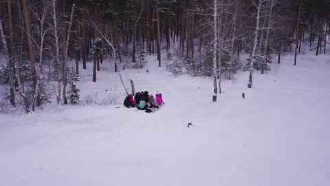 Sitting around a campfire with family and friends in winter forest. Friends sit around a fire in winter. Friends chat, have fun, fry potatoes, tell funny stories. Flying from drone, aerial view