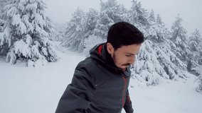 Young traveler guy walking in a snowy mountain, inside frozen trees and recording selfie video. 