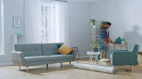 Time-Lapse: Happy Young Couple Moves into New Apartment, Arranges Furniture, Hanging Paintings, Resting after Everything is Done. Bright Modern House with Big Windows and Stylish Furniture.