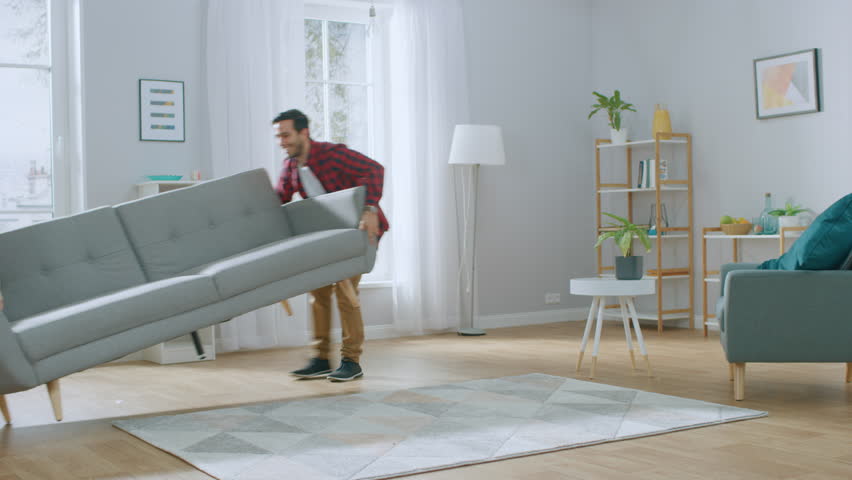 Happy Young Couple Moving New Couch into the Living Room, Fall on it to Rest. Bright Modern Apartment with Stylish Furniture. Royalty-Free Stock Footage #1022087902