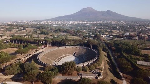 The ruins of a Roman amphitheater in Pompeii overshadow by Mount Vesuvius