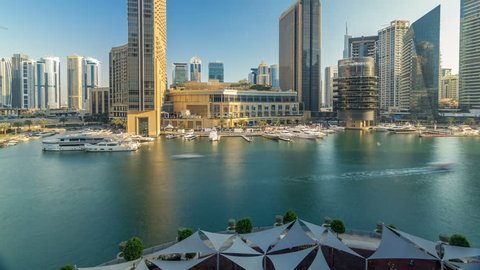 Aerial vew of Dubai Marina with shoping mall, restaurants, towers and yachts timelapse, United Arab Emirates. Top view of canal at evening before sunset