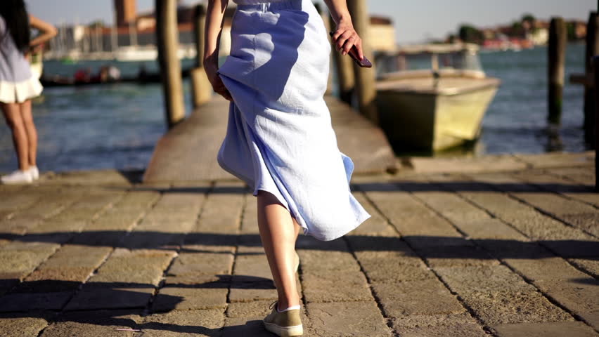 Slow motion of millennial female tourist running on pier for making photo of floating gondola on Venice Grand canal, carefree woman traveller enjoying time for trip to Italy during summer holidays