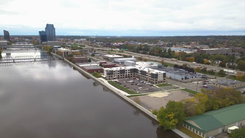 Aerial view of Grand River and surrounding area in Grand Rapids in Michigan, USA. Drone moves forward toward riverbank and highway.