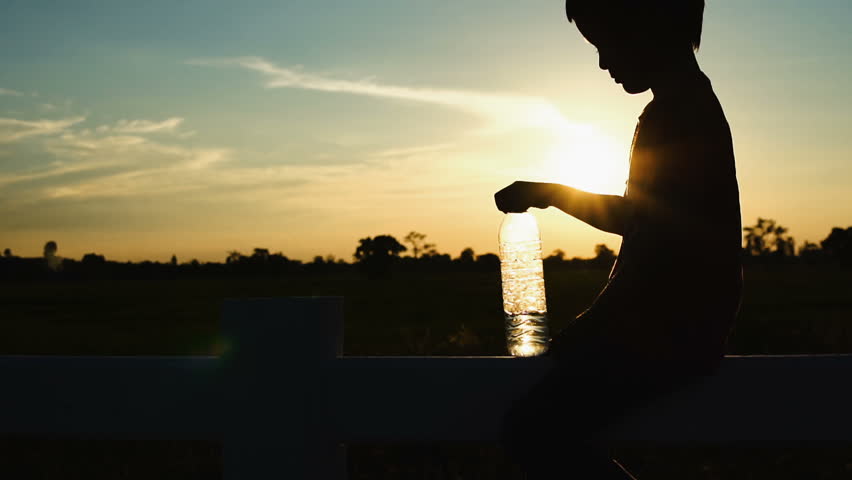 Happy Boy playing with water bottle At sunset Time. Slow motion