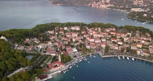 Small Croatian village built on the sea front, during sunset, filmed from the air