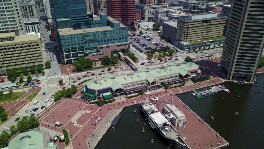Angled down lowering shot over the harbor of Baltimore and the streets with the buildings.