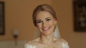 Portrait of a bride in a wedding dress. The bride dresses in the hotel. Video. happy bride