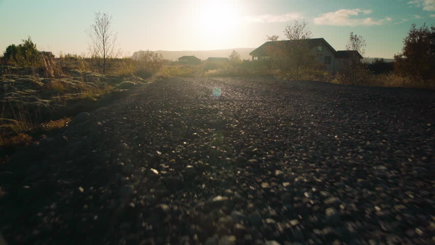 Low angle moving down a gravel road at sunset - animal POV close to the ground