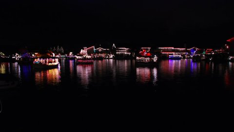 Boat parade on a lake with Christmas lights reflecting on the water - part one - HD.  Stock Video