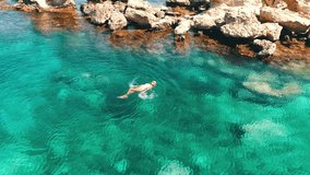 Summer image of beautiful girl swimming and lying on the back in the turquese sea water. Slim tanned body. Amazing sea landscape. Happy vacation and relaxing. Cyprus Green bay.