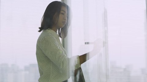 Focused Japanese woman writing an equation with a marker on glass and problem solving in a contemporary office with bright natural lighting. Medium to close up shot on 4k RED camera.