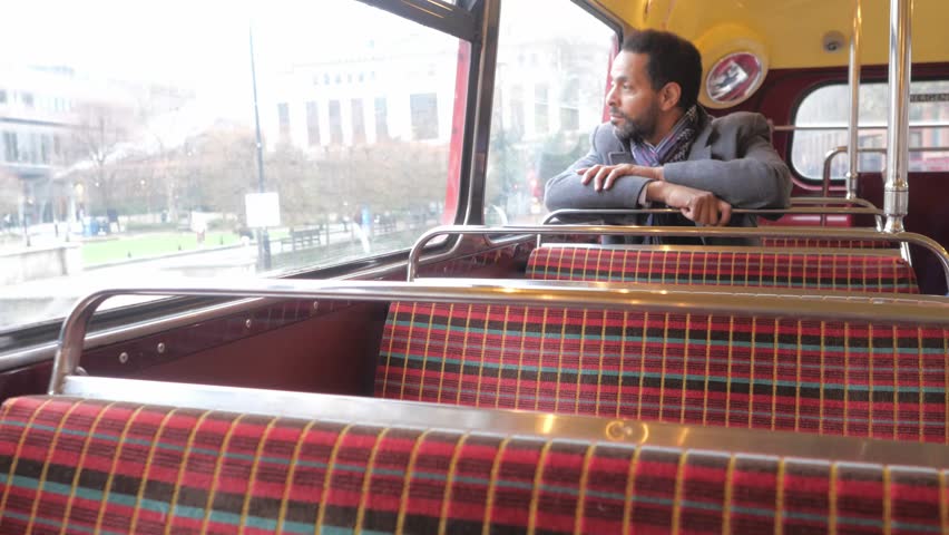 Man sits in an old London bus while travelling through the city