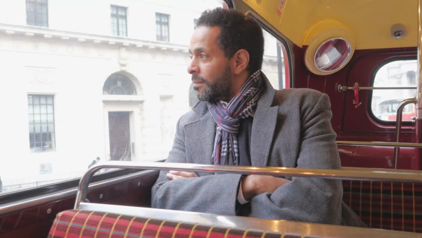 Man sits in an old London bus while travelling through the city