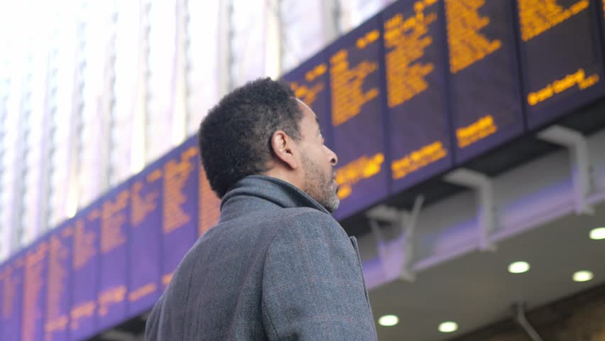 businessman reads the timetable of a train station
