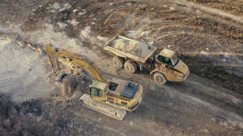 Fort Collins, CO, USA - January 7, 2019: Aerial view of an excavator loading a truck on a construction site. Heavy industry from above. Industrial dusty background.: redactionele stockvideo