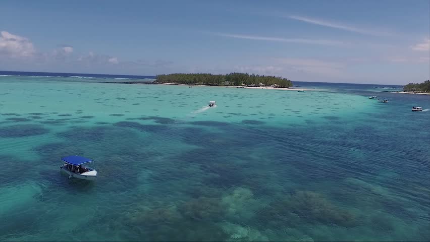 Coral reef area of the island isle of mauritius with speed boats moving around next to the coastline
(drone shot)
