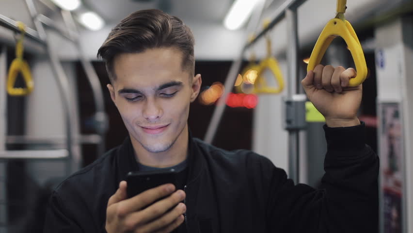 Happy businessman cheering celebrating looking at smartphone. Young urban professional successful business man receiving good news riding in public transport. He holds the handrail Royalty-Free Stock Footage #1022137771