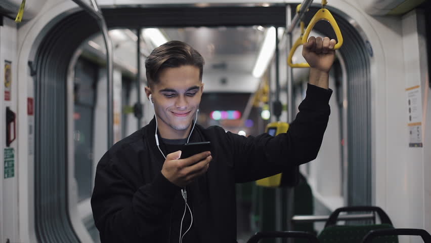 Happy businessman cheering celebrating looking at smartphone. Young urban professional successful business man receiving good news riding in public transport. He holds the handrail Royalty-Free Stock Footage #1022137774