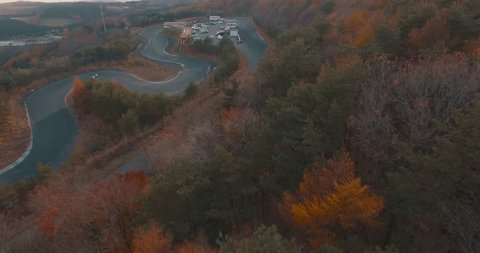 Aerial Drone Shot of a Drifting Race Track Nestled in the Mountains Covered in Orange Fall Leaves.