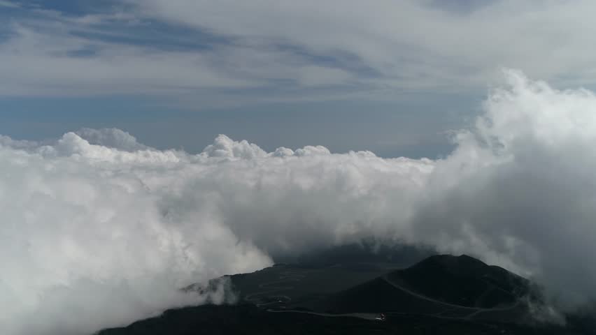 High altitude aerial footage turning left towards Mount Etna summit above clouds it is an active stratovolcano on the east coast of Sicily Italy in the Metropolitan City of Catania 4k resolution