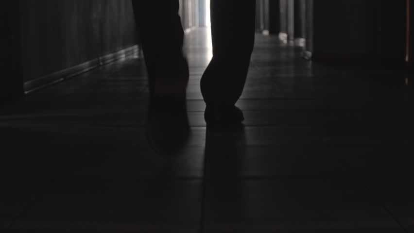 Dolly with low-section of silhouette of legs of man walking along hallway towards the camera Royalty-Free Stock Footage #1022145319