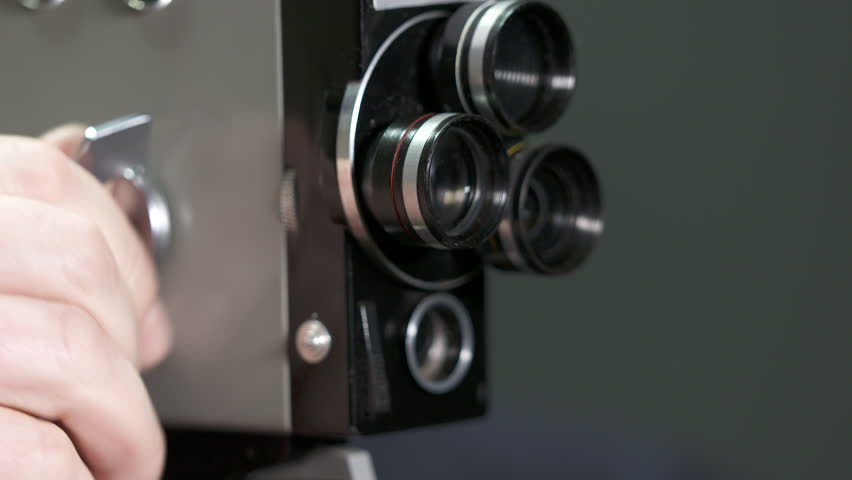 Man filming with vintage 8mm film movie camera. Winding and starting the motor.