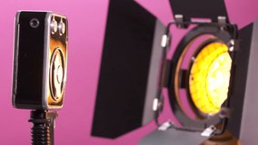 Vintage 8mm film movie camera and tungsten Fresnel light on pink background. Old Soviet Russian camera with mechanical motor rotating. Close-up dolly shot.