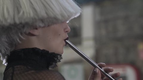 Kharkiv, Ukraine 13.12.2018
Close up in profile of blonde girl pretty face exhaling hookah smoke from a pipe