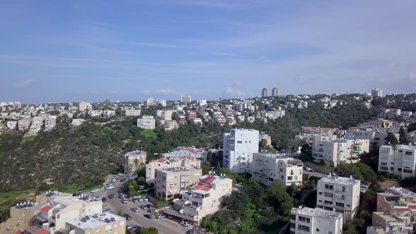 Aerial footage of the city of Haifa, Israel above and over the slopes of Mount Carmel.
