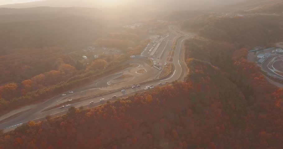 Wide Aerial Drone Shot Tracking Two Race Cars Drifting Around a Hard Curve on a Mountain Race Track.