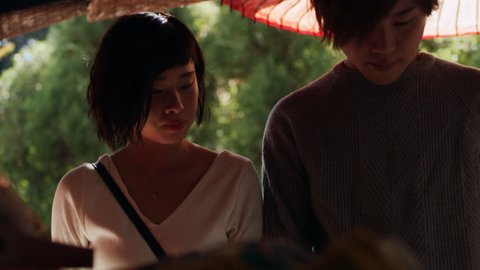 Young couple in love shopping and looking at items on a sidewalk vendor stand in Kyoto, Japan with soft shaded lighting. Medium shot on 4K RED camera.
