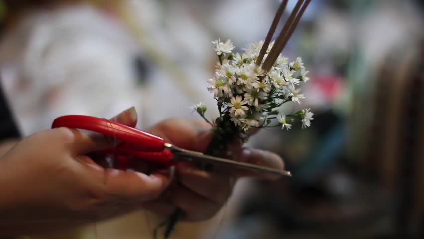 Woman making joss stick with flower decoration to use in a buddhist traditional festival.