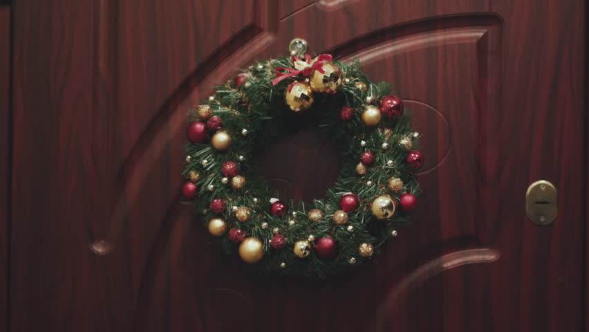 Wreath Christmas on the door. Hand of a man who knocks at the door