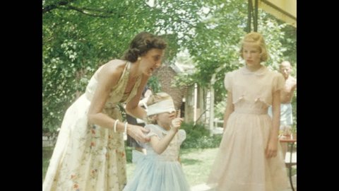 1960s: UNITED STATES: children attend birthday party. Girl plays pin the tail on the donkey. Children pose for camera. Girls run to camera. Girls in party dresses