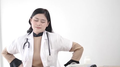 Depressed Asian doctor back ache indoor, slow motion.