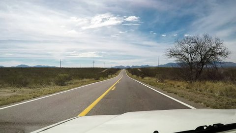 Tombstone, AZ / USA - August 1, 2018: Point of view of driver driving on a highway in South Central Arizona. Clip reveals a vacant and empty two lane road out in the country.