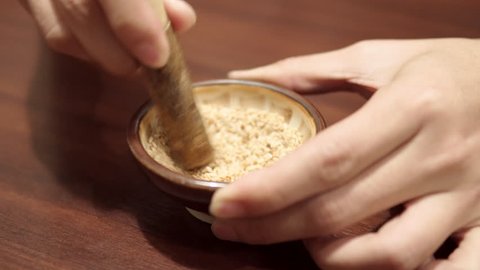 Male hand crushing sesame seeds in a small bowl at Japanese restaurant. Food ingredient. 4K resolution video