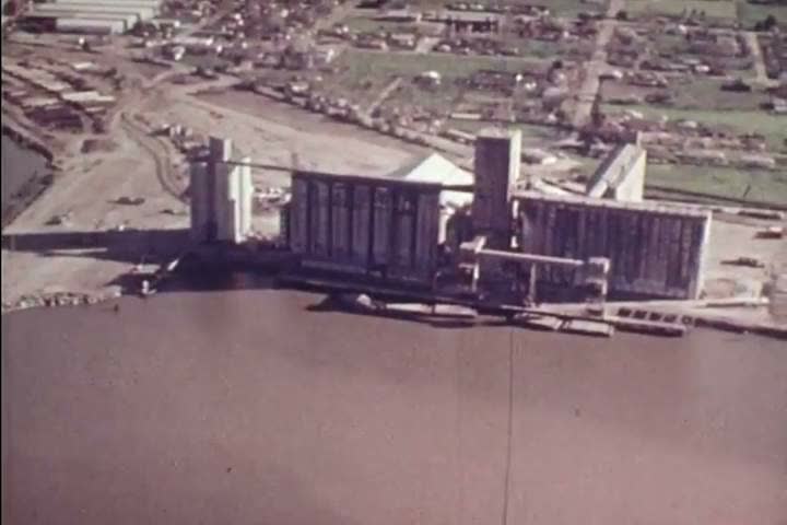 CIRCA 1973 - An aerial view of an inland port is shown as a freighter comes in.