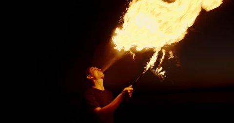Cool fire show artist breathes fire in dark air, performing amazing stunts - slow motion 4k