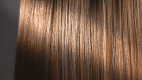 Hair. Beautiful healthy long smooth flowing brown hair close-up texture. Dyed straight shiny hair background, coloring, extensions, cure, treatment concept. Haircare. Slow motion 4K UHD video