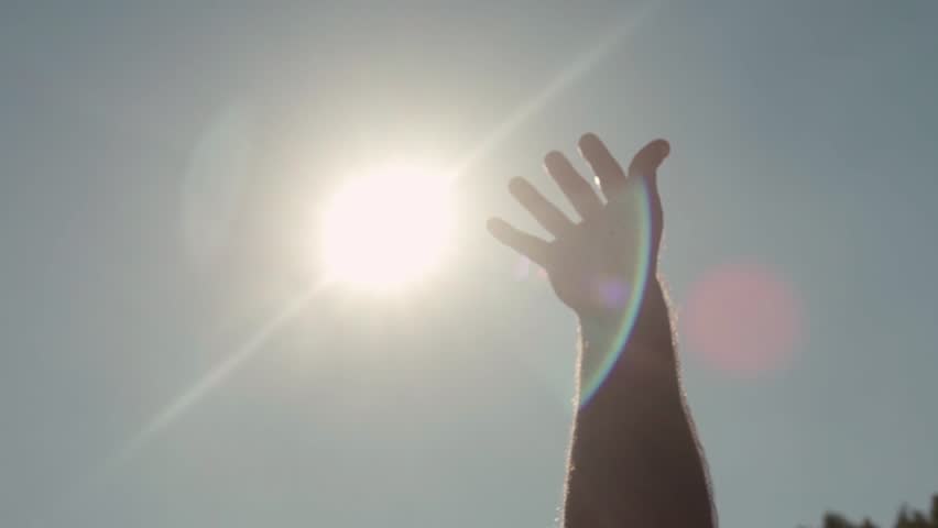Close-up of hand reaching for sun. Man reaches out to sky in pleasure from warm rays of bright sun. Swimming in summer sun | Shutterstock HD Video #1022235772