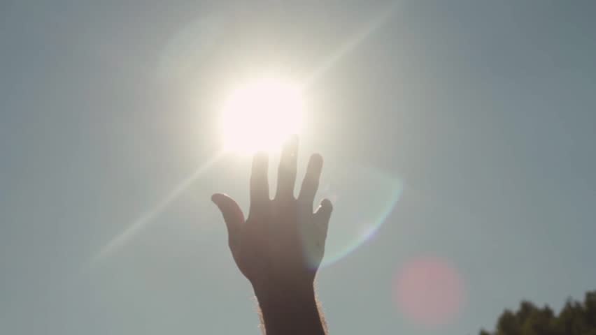Close-up of hand reaching for sun. Bright sunlight breaks through fingers of outstretched hand to sky | Shutterstock HD Video #1022235781