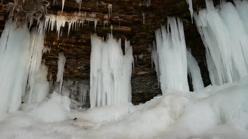 Low angle view of the mostly frozen Wequiock Falls near Green Bay, Wisconsin with large, frozen icicles and water flowing.