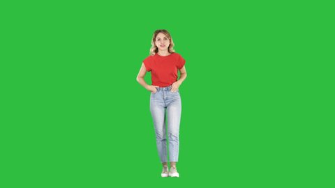 Blond woman walking with hands in her pockets and talking to camera on a Green Screen, Chroma Key.