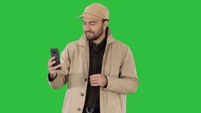 Young man making a video call from his mobile phone while walking on a Green Screen, Chroma Key.