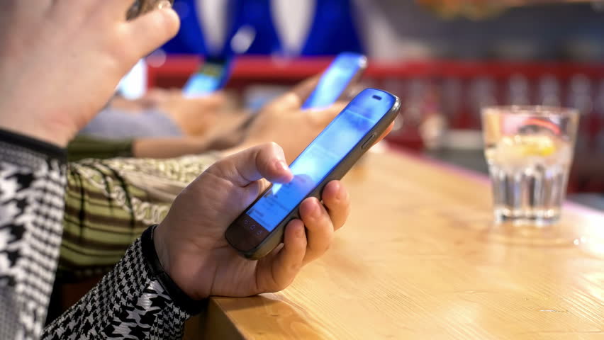 people using smartphones and drinking in the pub: mobile phone addicted people